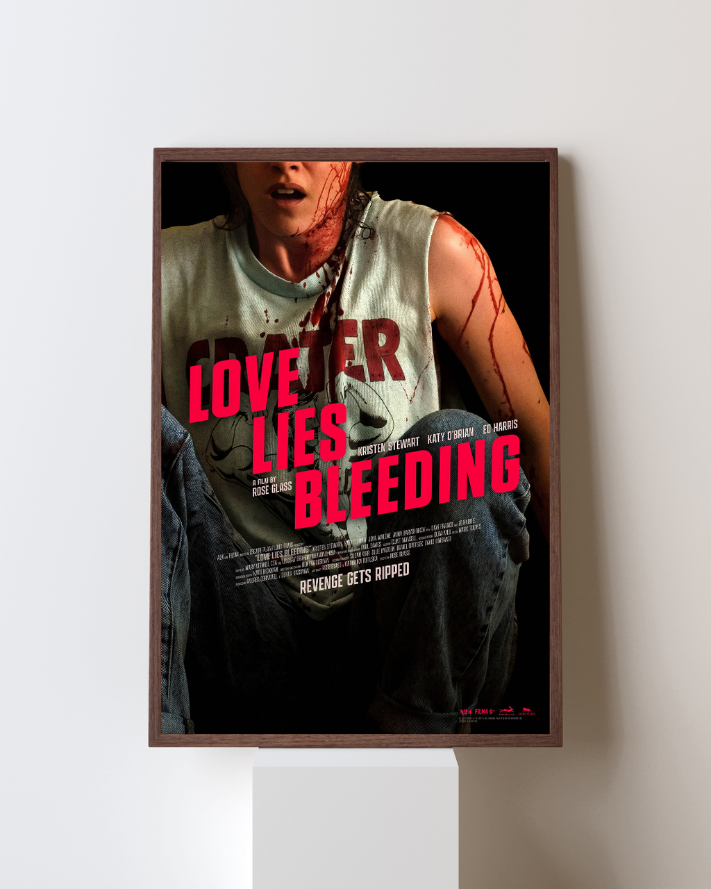 Affiche encadrée du film Love Lies Bleeding représentant une femme couverte de sang dans une scène dramatique, accrochée dans un intérieur moderne, inspirée du film avec Kristen Stewart.
