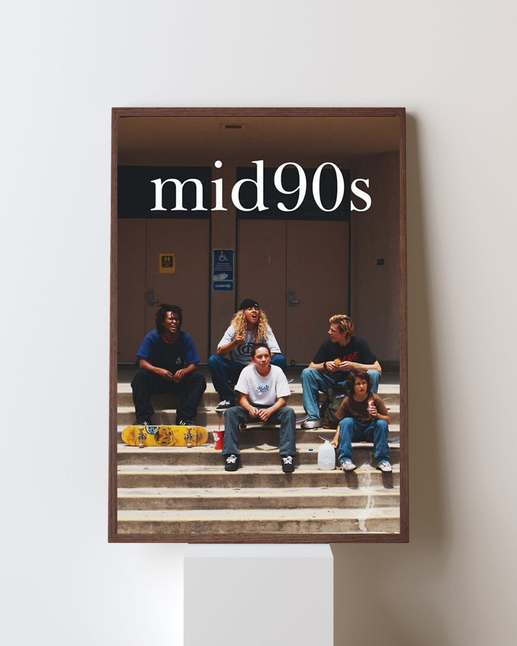 Affiche encadrée du film Mid90s représentant un groupe de jeunes skateurs assis sur des marches dans une ambiance rétro, accrochée dans un intérieur moderne, inspirée de la culture skate des années 90.
