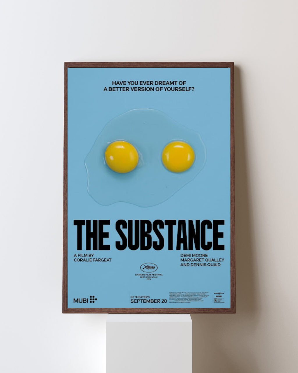 Affiche encadrée de The Substance avec deux jaunes d’œufs sur fond bleu, installée dans un intérieur moderne, apportant une touche artistique et minimaliste.
