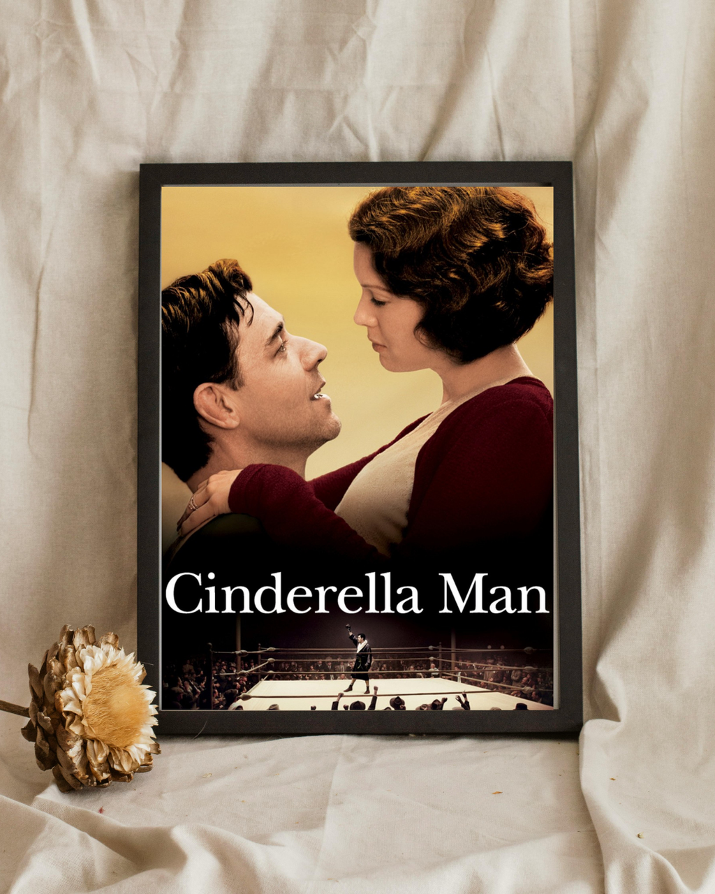 Affiche encadrée du film Cinderella Man représentant un moment intime entre un couple avec un ring de boxe en arrière-plan, accrochée dans un intérieur moderne, style biopic sportif.
