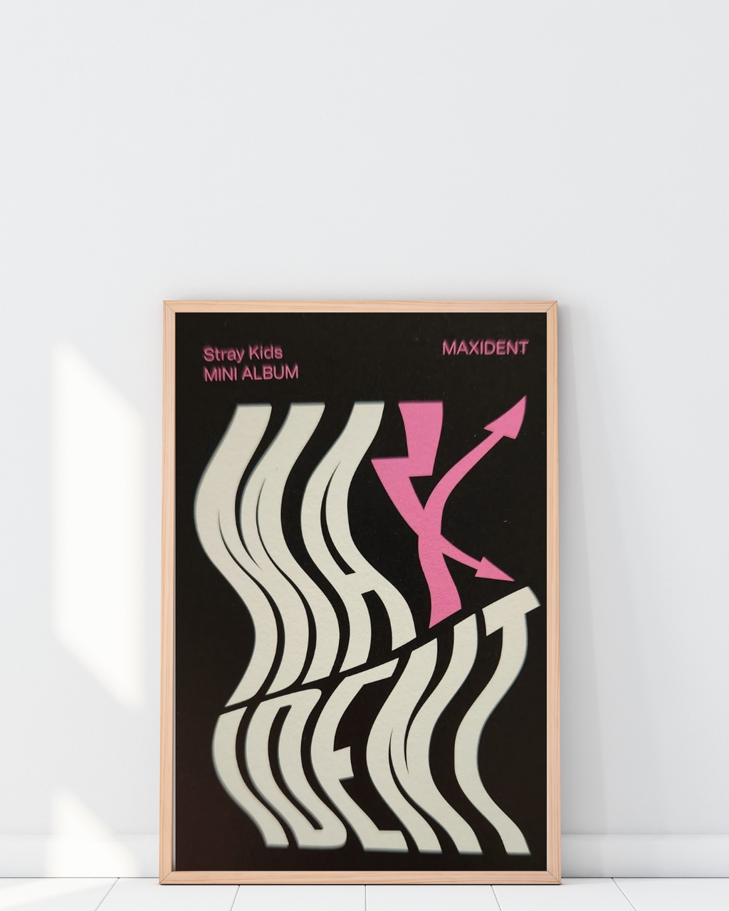 Poster Stray Kids Maxident encadré dans un intérieur moderne avec décoration murale minimaliste et artistique, contraste noir et blanc avec accents roses, style contemporain K-pop, Poster Hub Studio.
